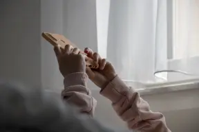 Person holding their phone above them whilst lying in bed